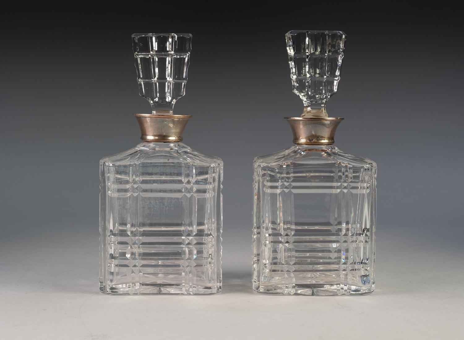 PAIR OF CUT GLASS OBLONG SPIRIT DECANTERS with panel cut flat stoppers and silver clad necks, 10" (