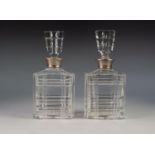 PAIR OF CUT GLASS OBLONG SPIRIT DECANTERS with panel cut flat stoppers and silver clad necks, 10" (