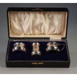 George V BOXED SILVER CONDIMENT TRIO of plain early Georgian style with blue glass liners (lacks