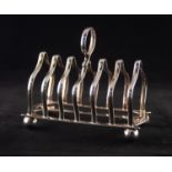 A LATE VICTORIAN SILVER SEVEN DIVISION TOAST RACK, with central handle, standing on ball feet,