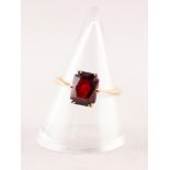 18ct GOLD DRESS RING WITH AN OBLONG GARNET in a six claw crown setting, 2.2gms, ring size 'M'