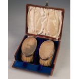 PAIR OF GEORGE V SILVER BACKED MILITARY HAIR BRUSHES oval and hollowed and engraved with foliate