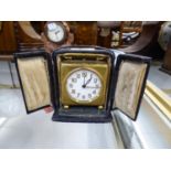 GILT METAL CASED TRAVELLING BEDSIDE CLOCK with carrying handle, contained in an outer leather