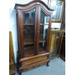 A MAHOGANY PERIOD STYLE DISPLAY CABINET WITH ARCHED TOP, TWO GLAZED DOORS, DRAWER BELOW, ON STUMP