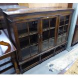 AN OAK LIBRARY BOOKCASE, ENCLOSED BY THREE PANE PANEL DOORS, ON BOBBIN TURNED SUPPORTS WITH PLAIN