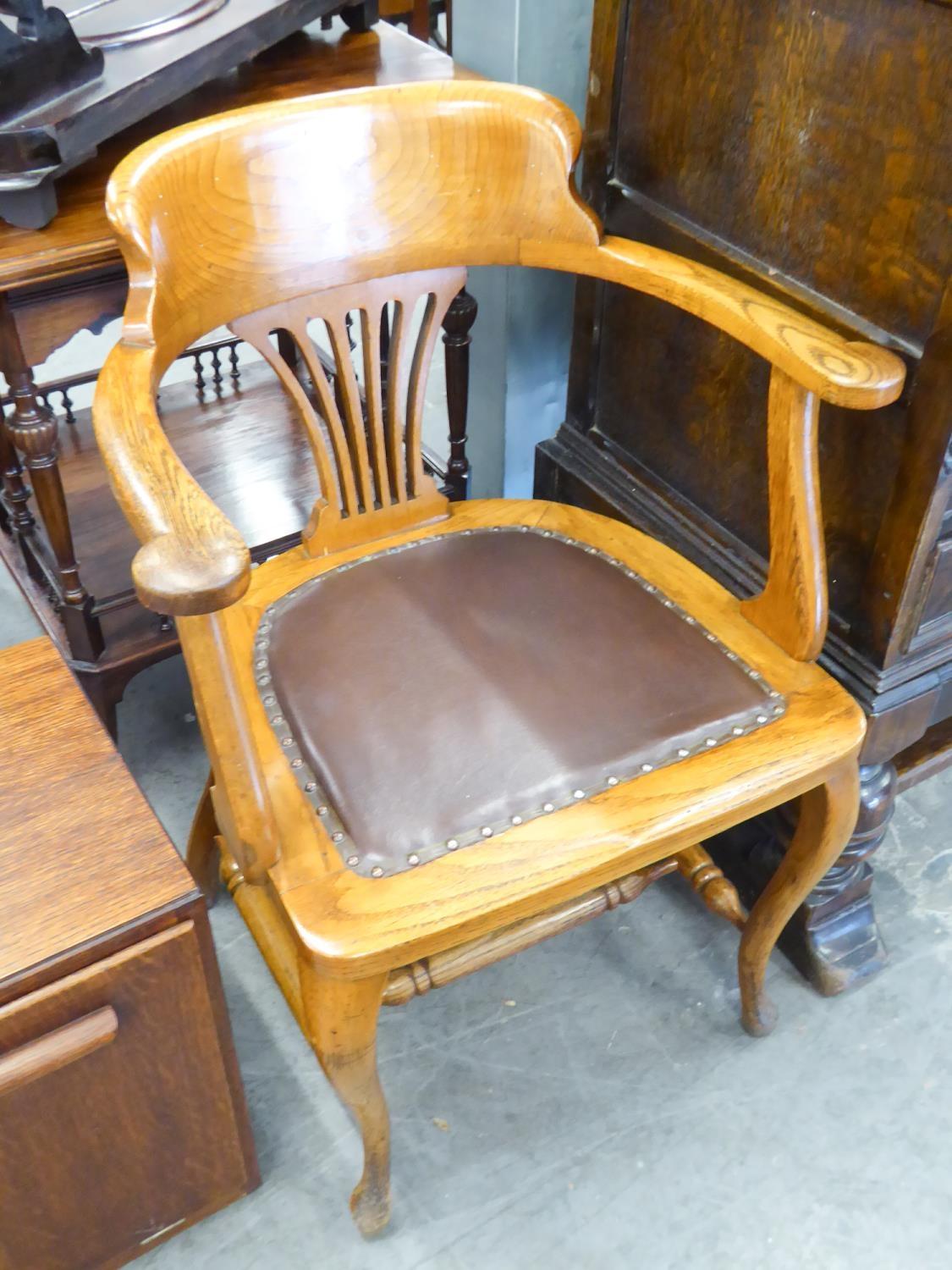 AN OAK FRAMED CAPTAIN'S ARMCHAIR HAVING LEATHER SEAT