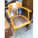 AN OAK FRAMED CAPTAIN'S ARMCHAIR HAVING LEATHER SEAT