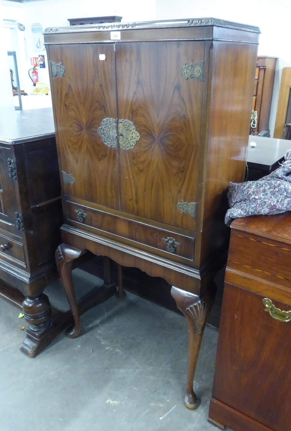 A MAHOGANY COCKTAIL CABINET, HAVING TWO DOORS OVER ONE LONG DRAWER, THE MIRRORED INTERIOR HAVING