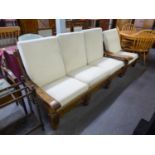 AN OAK FRAMED THREE SEATER SETTEE AND MATCHING LOUNGE ARMCHAIR, WITH LOOSE BACK AND SEAT CUSHIONS