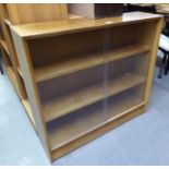 A POLISHED WOOD DWARF BOOKCASE WITH GLASS SLIDING DOORS