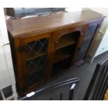 AN OAK LOW BOOKCASE WITH TWO LEAD GLAZED DOORS, WITH OPEN CENTRAL SECTION AND AN OAK TRESTLE STYLE