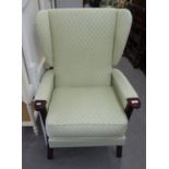 'PLUMBS' WINGED FIRESIDE ARMCHAIR, COVERED IN GREEN PATTERNED FABRIC