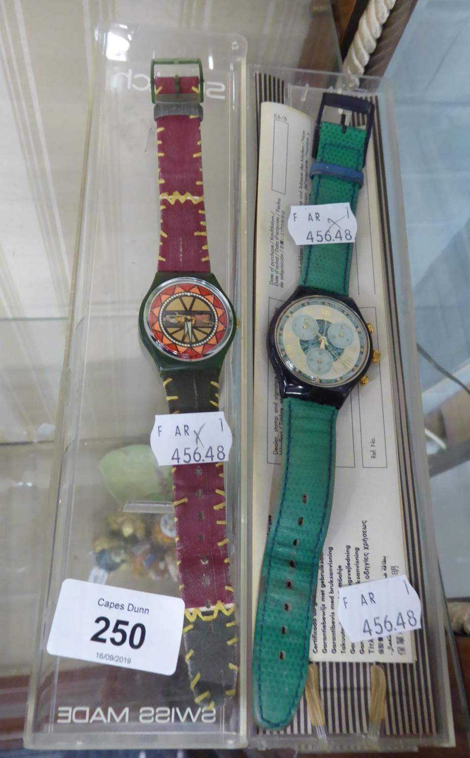 TWO SWATCH WRIST WATCHES, ONE WITH PINK AND RED AZTEC DESIGN, THE OTHER WITH GILT ROMAN NUMERALS AND