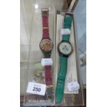 TWO SWATCH WRIST WATCHES, ONE WITH PINK AND RED AZTEC DESIGN, THE OTHER WITH GILT ROMAN NUMERALS AND