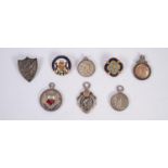 THREE INTER WAR YEARS SILVER CROWN GREEN BOWLS RELATED PENDANTS OR FOBS a RELATED SHIELD SHAPED