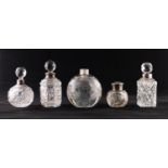 FOUR EARLY TWENTIETH CENTURY CUT AND PRESSED CLEAR GLASS SILVER RIMMED TOPPED SCENT BOTTLE AND AN