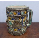 A MID EASTERN WHITE METAL MOUNTED FAYENCE MUG, enamelled in pale orange, blue and turquoise with