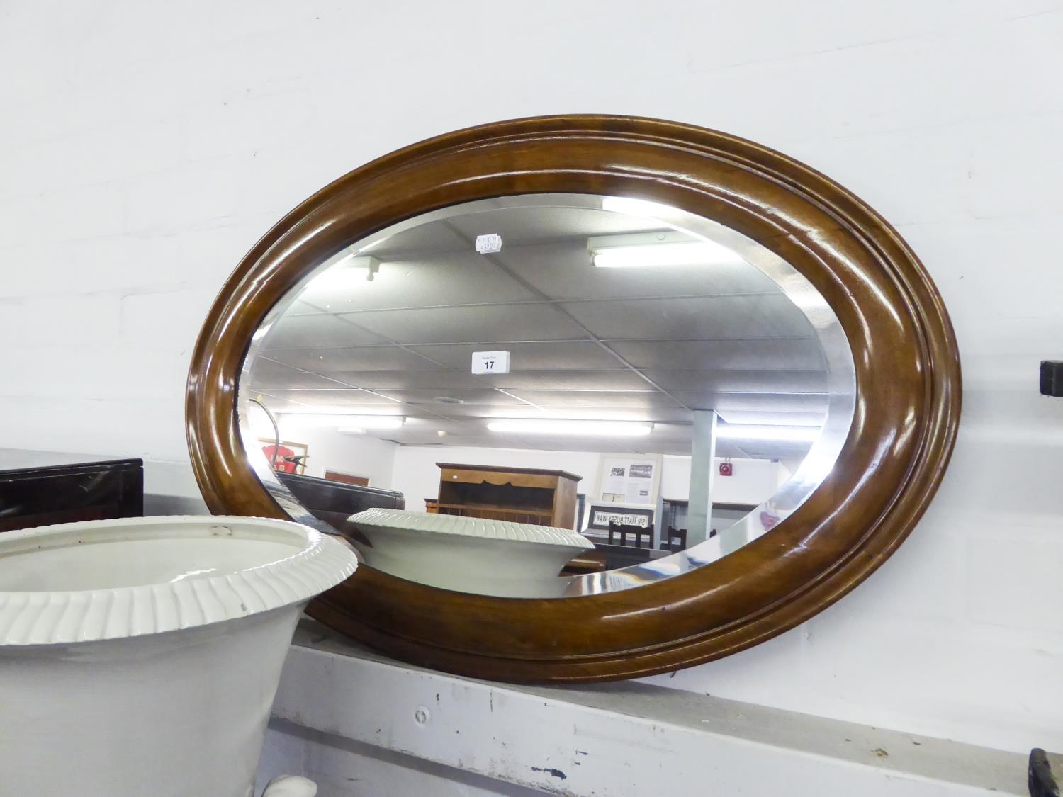 AN OVAL BEVELLED EDGE WALL MIRROR, IN MAHOGANY FRAME