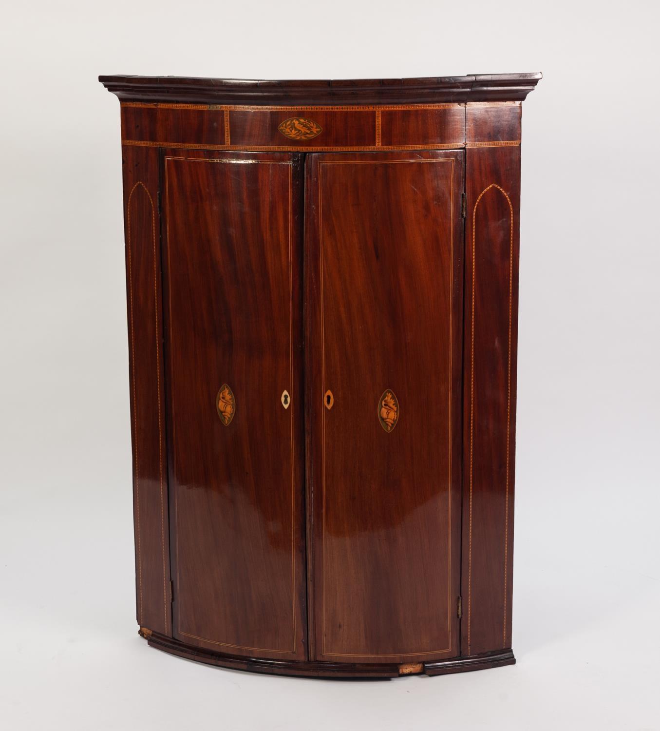 GEORGE III INLAID MAHOGANY BOW FRONTED CORNER CUPBOARD, the moulded cornice above a frieze with