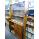 A TEAK BOOKCASE WITH GLASS SLIDING DOORS, ON AN ADVANCED CUPBOARD BASE, WITH TWO PANEL SLIDING