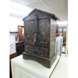 FAR EASTERN CARVED AND DARK STAINED SMALL CUPBOARD FORMED AS A TWO DOOR HUT, WITH SEATED AND OTHER