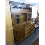 AN 'ADSHEAD' CABINET MADE DRESSER WITH RAISED PLATE RACK WITH GLAZED CUPBOARD, ON BASE WITH THREE