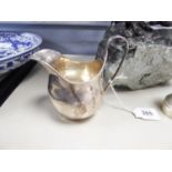 EDWARDIAN SILVER CREAM JUG, helmet shaped with raised reeded 'C' scroll handle, 4 1/4" (10.7cm) high