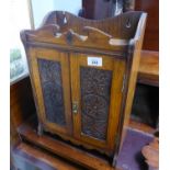 LATE VICTORIAN CARVED OAK SMOKER'S CABINET, of typical form with a pair of foliate carved cupboard