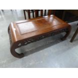 A CHINESE HARDWOOD COFFEE TABLE WITH PANELLED TOP AND PIERCED FRIEZE AND CURVED END SUPPORTS