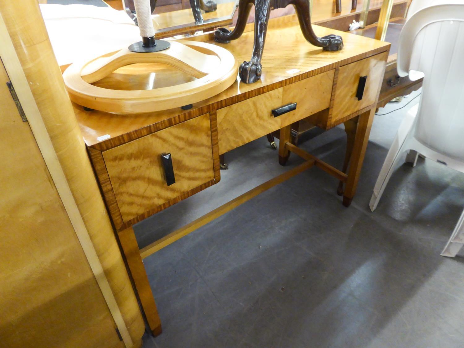 AN ART DECO KNEEHOLE DRESSING TABLE, TWO SMALL DRAWERS FLANKING A LONG CENTRAL DRAWER, RAISED ON