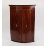 GEORGE III INLAID MAHOGANY BOW FRONTED CORNER CUPBOARD, the moulded cornice above a frieze with