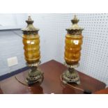 A PAIR OF ORNATE CAST METAL TABLE LAMPS WITH AMBER GLASS SHADES (2)
