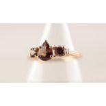 9ct GOLD RING SET WITH A TEAR SHAPED GARNET and flanked by two small circular white stones, 2.