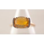 9ct GOLD RING WITH A FACETED OVAL OPAL in a four claw setting between a cradle shaped continuous