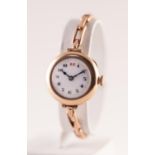 AN EARLY 20TH CENTURY LADIES 9CT GOLD CASED WRISTWATCH The circular white enamel dial with red and