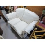 A TWO SEATER SETTEE COVERED IN WHITE FABRIC, WITH LOOSE CUSHIONS