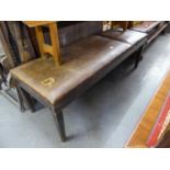 AN ANTIQUE DOCTORS COUCH/MASSAGE TABLE, WITH ADJUSTABLE HEAD REST, COVERED IN BROWN LEATHER (TEAR IN