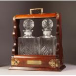 EARLY 20TH CENTURY MAHOGANY & BRASS MOUNTED TWO BOTTLE TANTALUS the front of lifted base hinged with