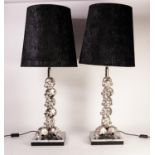 PAIR OF MODERN WHITE METAL TABLE LAMPS, each cast with eight skulls, on a square base, with black