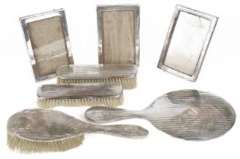 Three silver photograph frames, a four piece silver brush and mirror set