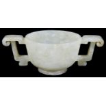 A Chinese pale celadon jade carved twin handled cup of archaic design