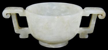 A Chinese pale celadon jade carved twin handled cup of archaic design