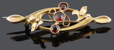 A Victorian 9ct gold and three stone garnet scroll brooch