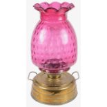 A large Victorian brass oil lamp with cranberry glass shade