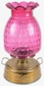 A large Victorian brass oil lamp with cranberry glass shade