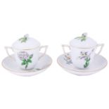 A pair of Herend porcelain twin handled botanical covered chocolate cups and stands