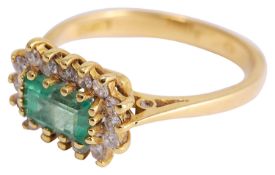 A delicate rectangular cut emerald and diamond cluster ring