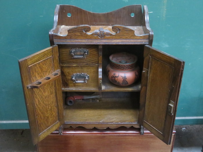 CARVED FRONTED OAK TWO DOOR SMOKER'S CABINET WITH FITTED INTERIOR AND ORIGINAL TOBACCO JAR (AT
