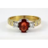 A yellow metal (tested 18ct gold) ring set with an oval cut red sapphire and diamond set