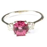 An 18ct white gold ring set with a cushion cut pink sapphire and diamond set shoulders, (Q).